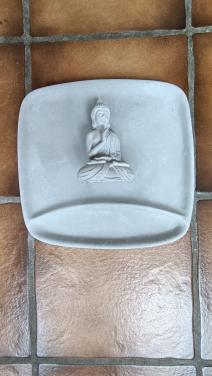 Boeddhabeeldje op een bordje / tray. Beide van gips of soort beton.