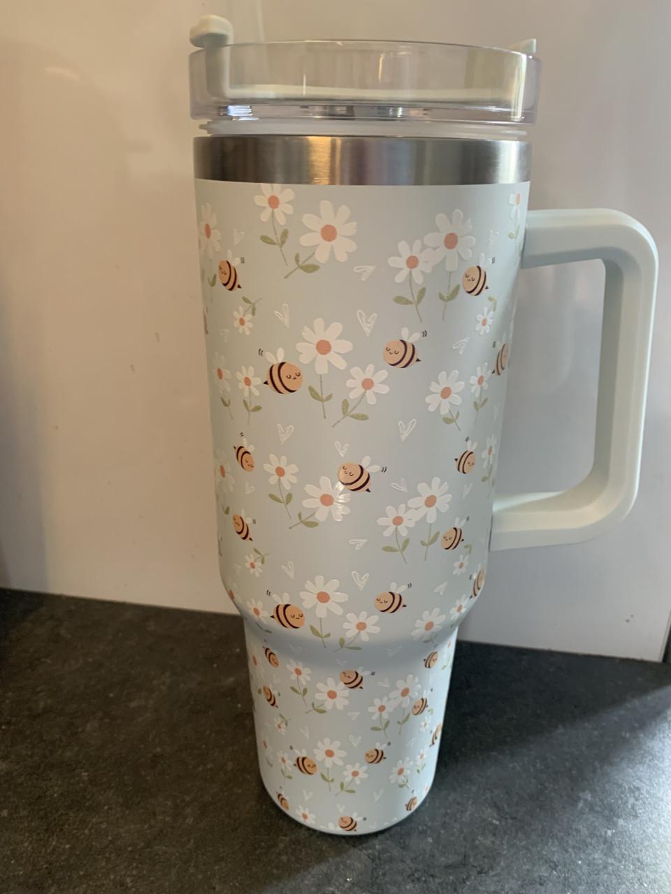 Tumbler beker heeft een vrolijke print van bijen en bloemen.