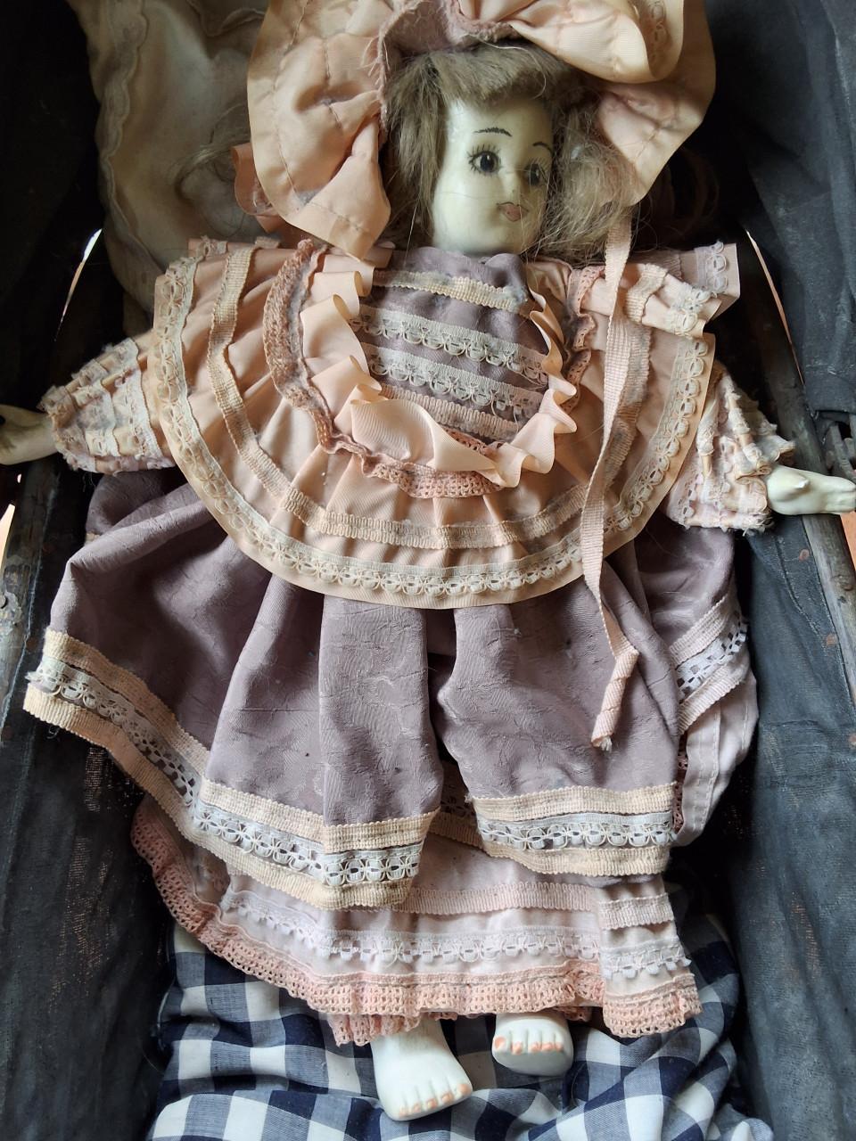 Antieke poppenwagen met porseleinen pop