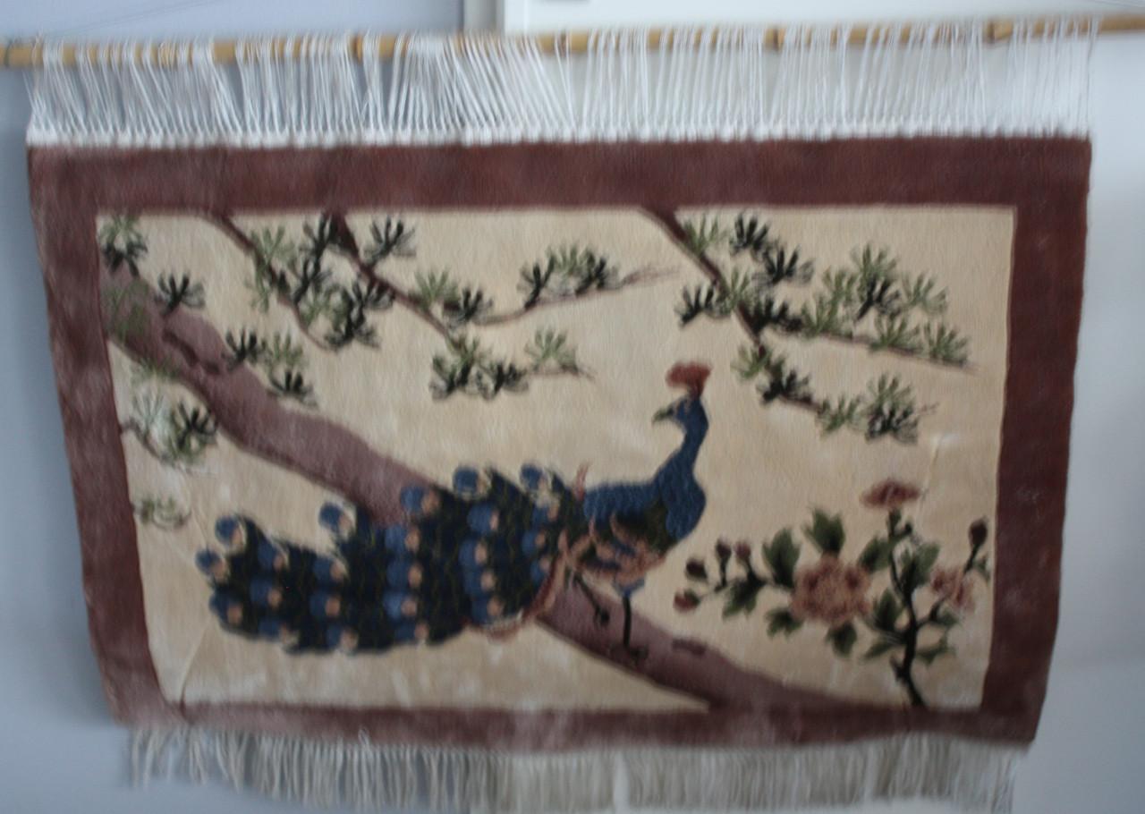 Geknoopt wandkleed met afbeelding van pauw.