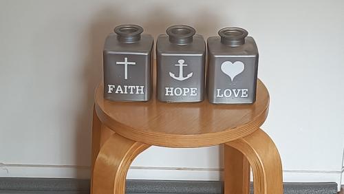 3 Zilverkleurige flesjes met in witte opdruk de tekst Faith, Hope, Love