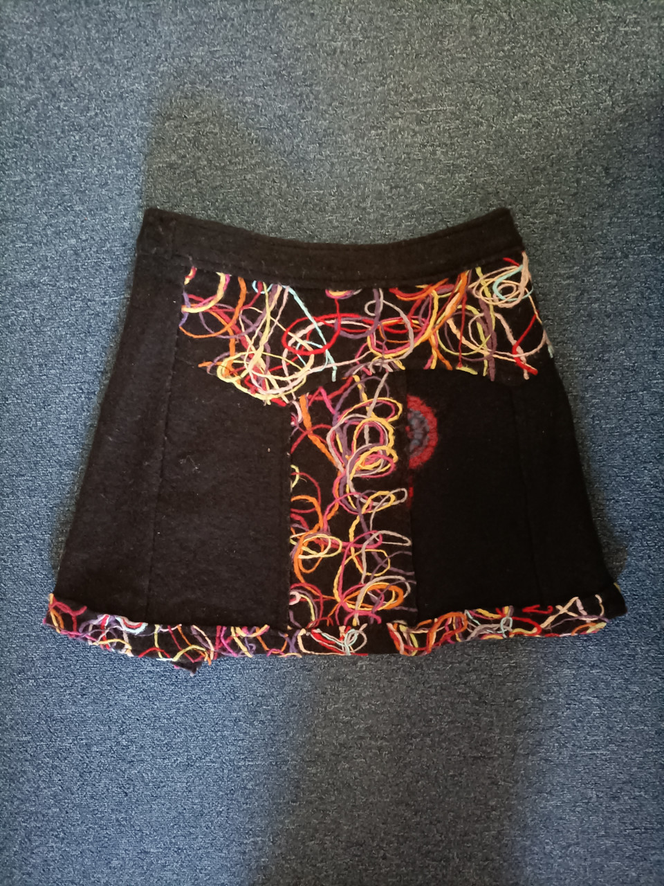 Rok gekleurd, ondergrond zwart. Leuk met knopen. Maat S 36/38.