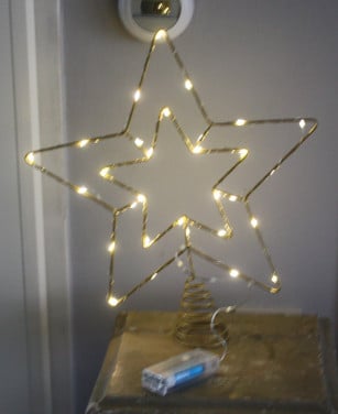 Goed kleurige metalen kerststerpiek met lichtjes