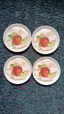 4 onderzetters. Hard plastic. Wit met een appel erop.