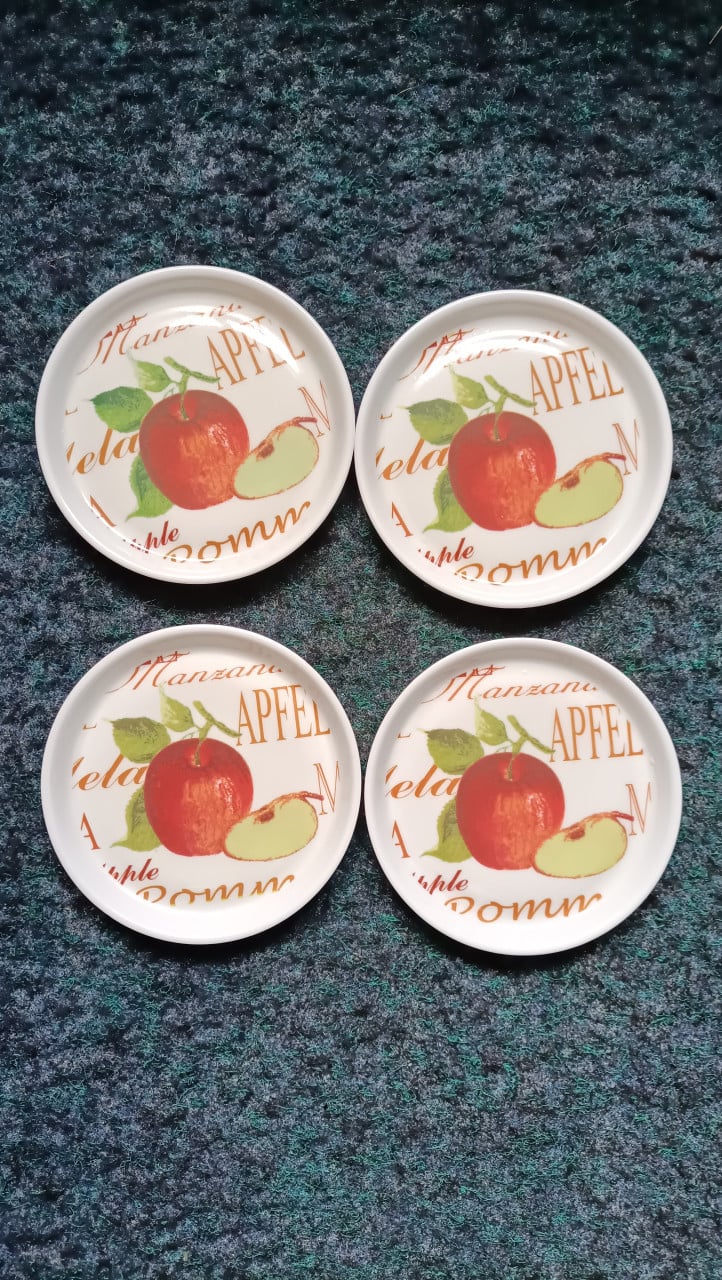 4 onderzetters. Hard plastic. Wit met een appel erop.