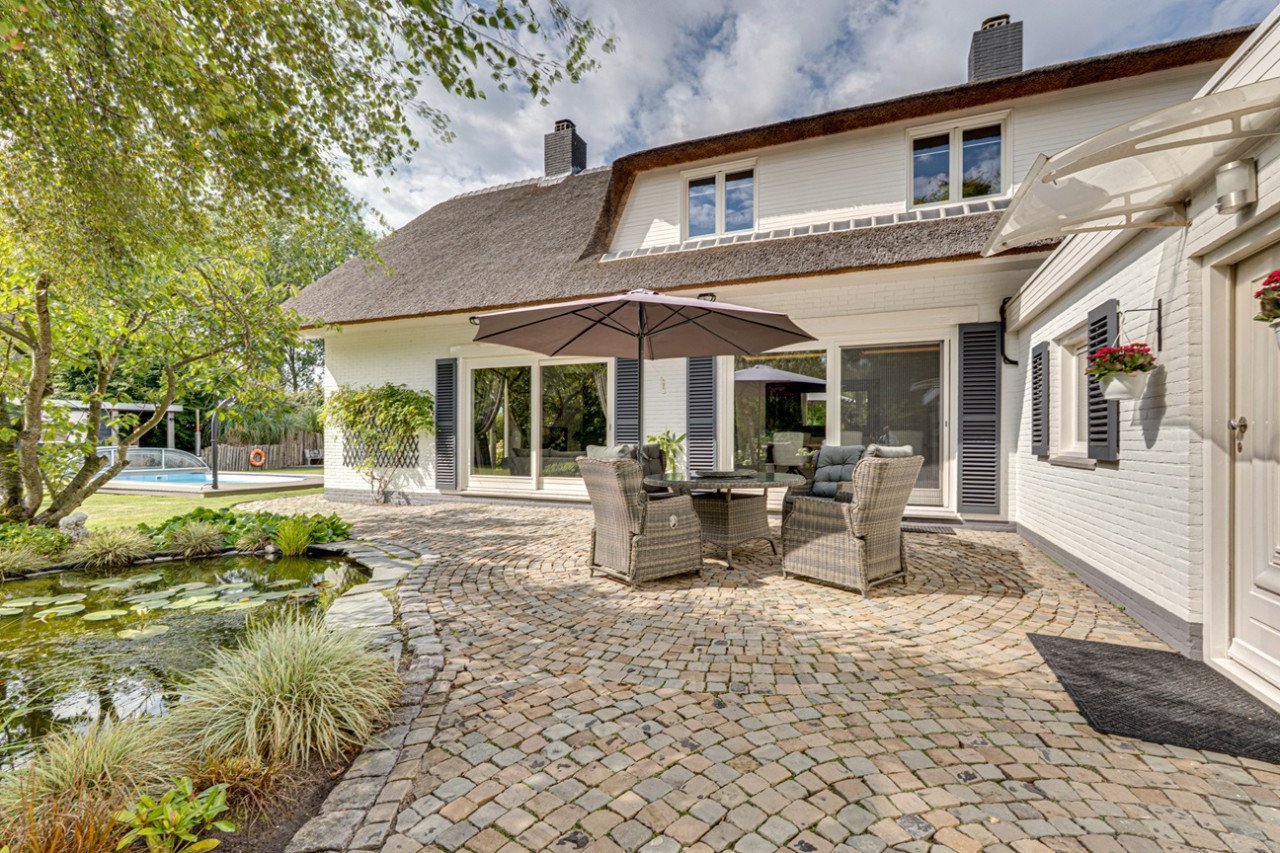 Rietgedekte villa met een overdekt zwembad.