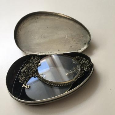 Een pince-nez in een zilveren doosje