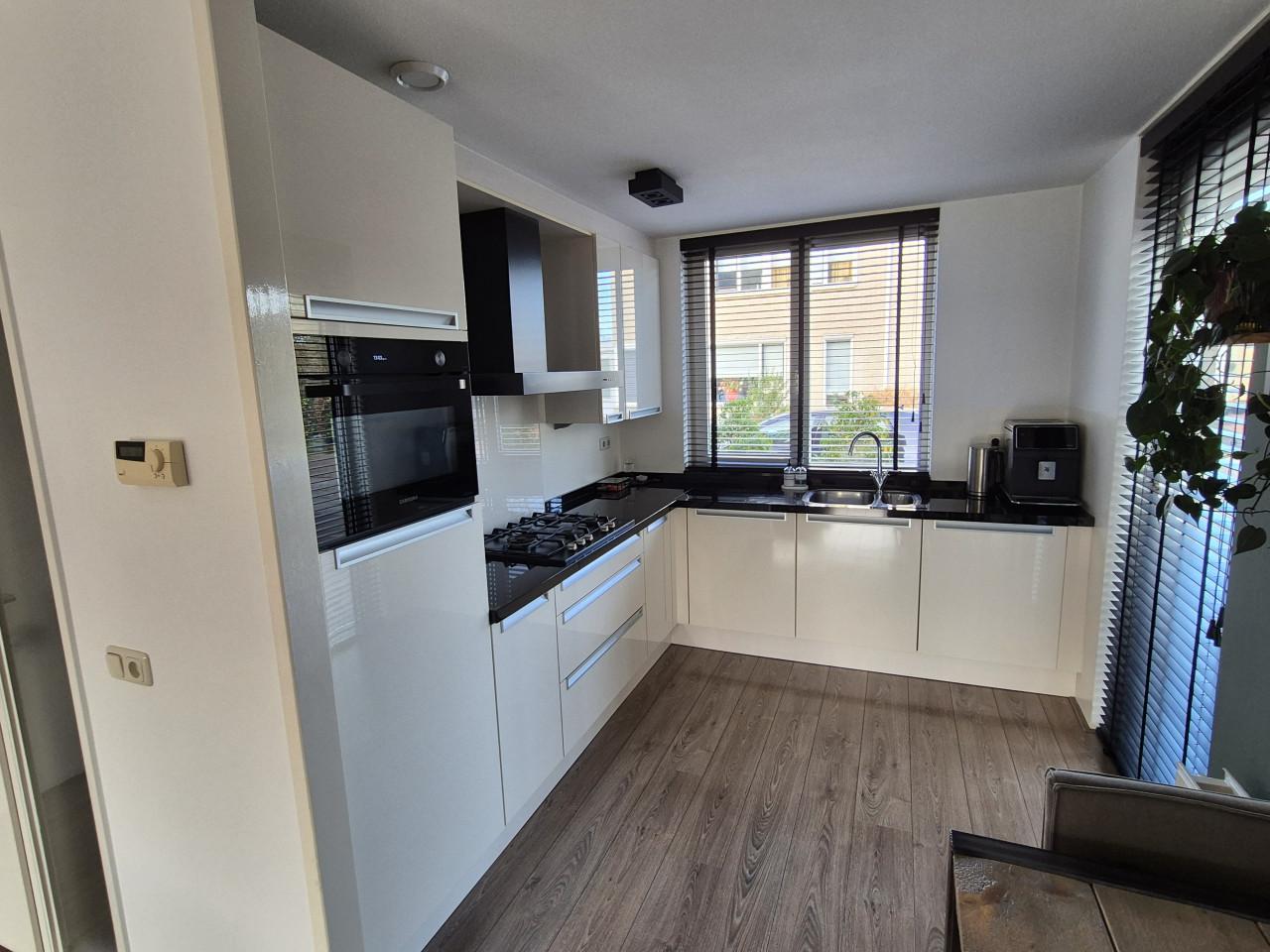 Nette hoogglans hoekkeuken met zwart granieten blad.