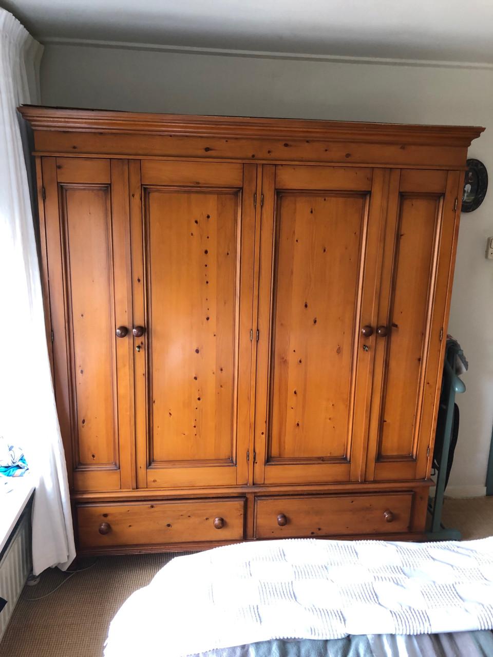 Grote houten kledingkast met deuren en lades.