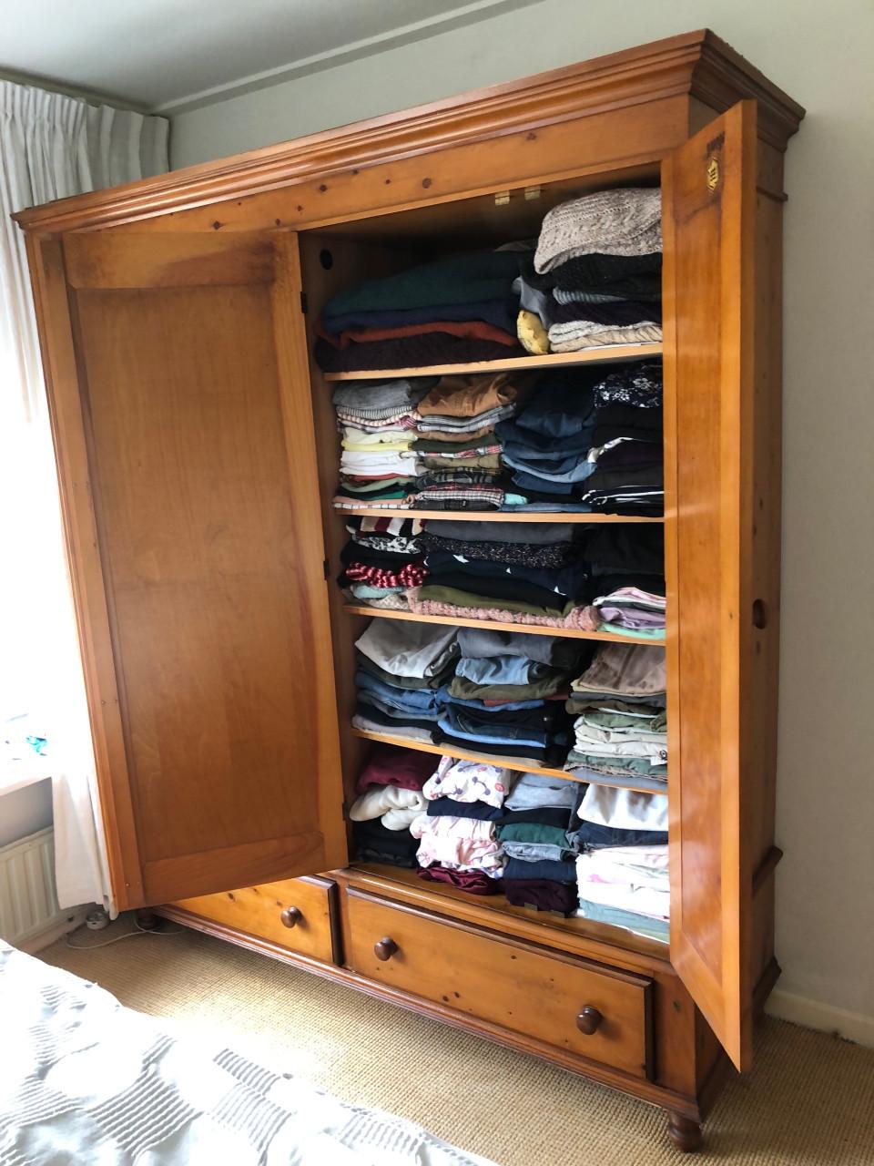 Grote houten kledingkast met deuren en lades.