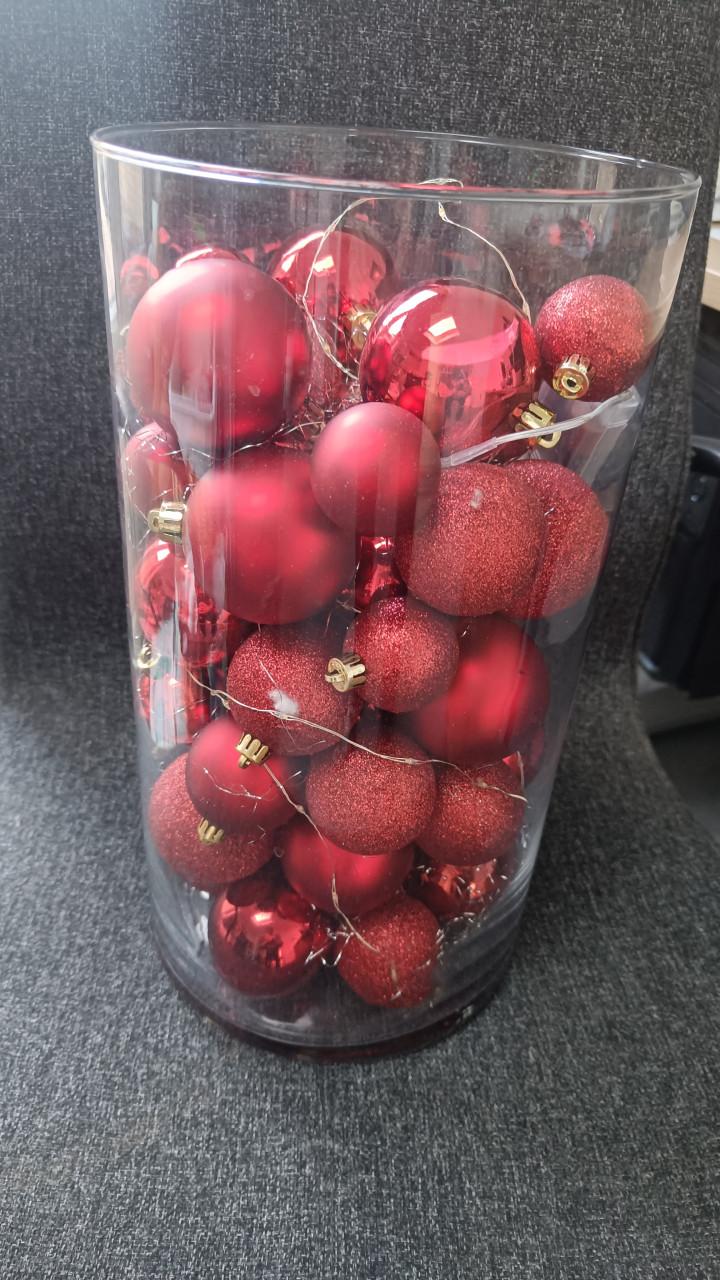 Glazen vaas met rode ballen en verlichting