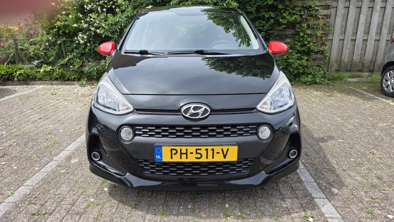 Hyundai I10 2019 met 69300 km Zwart met rode spiegels en sierstrippen.