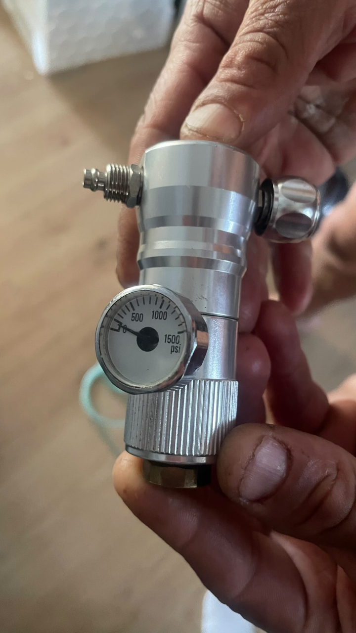 800g wegwerp CO₂-fles — levert de CO₂.  Drukregelaar met manometer