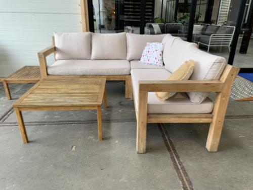 Een houten loungeset met kussens en 2 tafels, en regenhoes