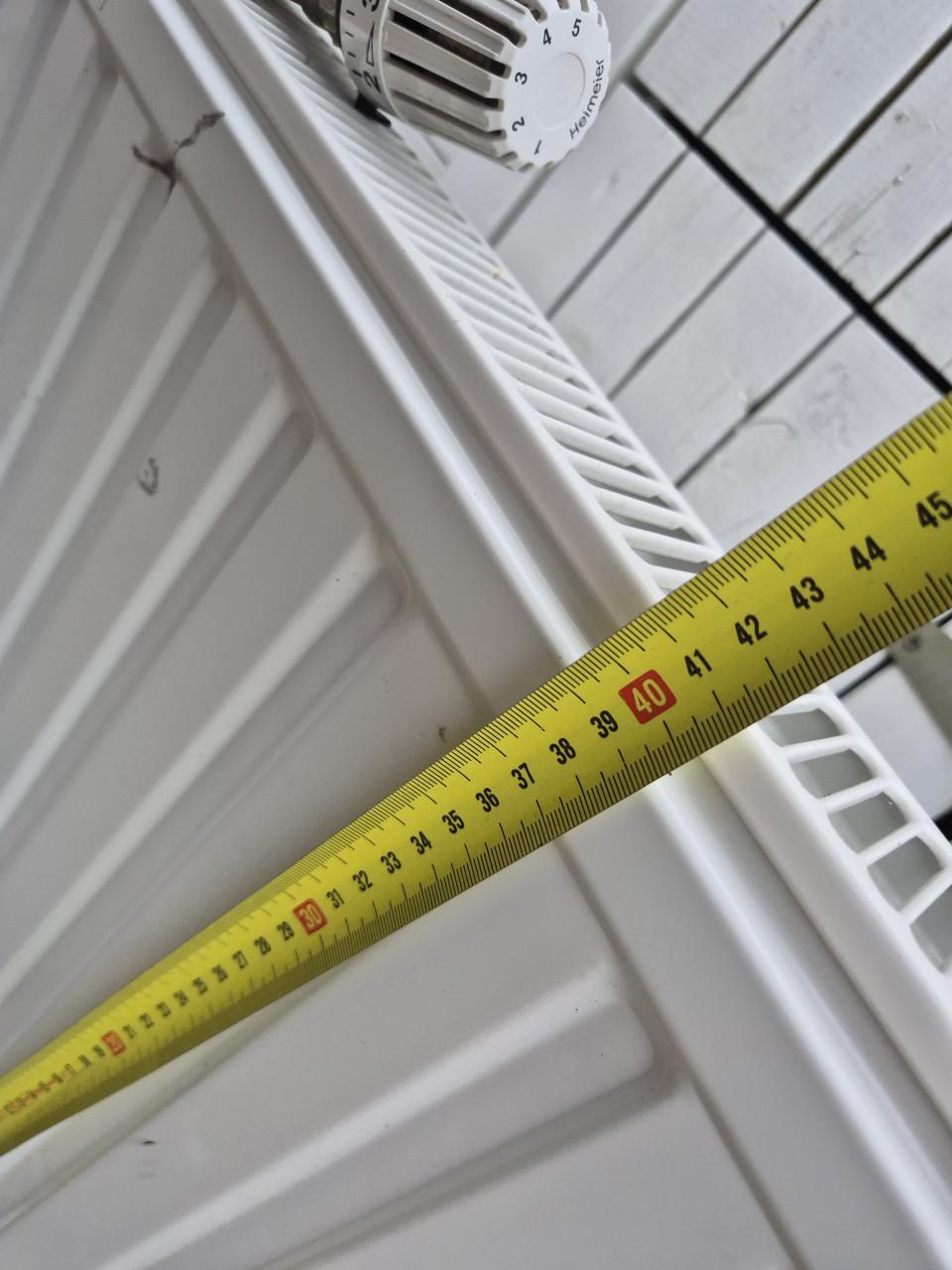 Nette radiator met ophangsysteem en thermostaatknop.