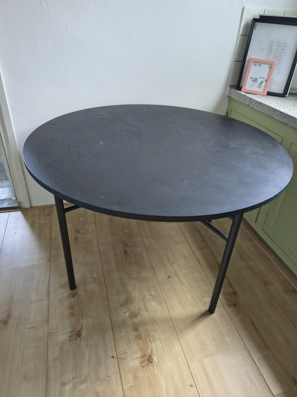 Prachtige ronde houten zwarte eettafel met metalen poten.