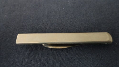 Dasspeld – metaal  Lengte onderkant 5,5 cm. Lengte bovenkant 4 cm.